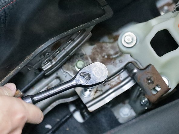 Use a 10m socket and remove the steel bracket located behind the shifter.