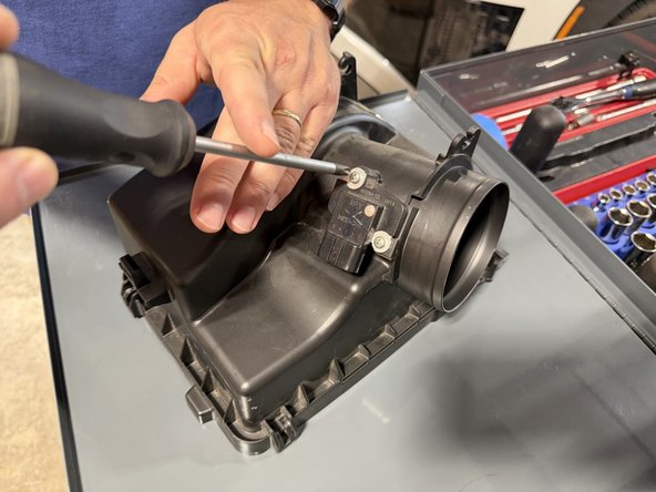 Remove the two screws and pull the MAF sensor off the stock cover. You reuse the MAF sensor and its gasket