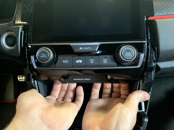 Use your hands and pry the lower section of the climate control towards you.