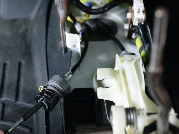 Flip the lock up and spin the shifter cable ring. This can be tough because you must spin it enough for the slot to align with the shifter. Once it aligns you can slide it out and the cable lock will twist back.