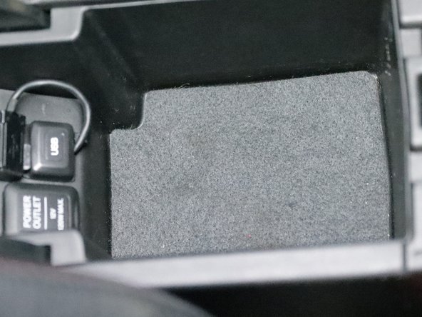 Inside of the center console armrest, there are two screws located under the felt liner. Remove them.