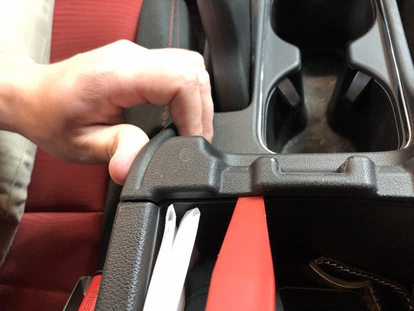 Open the center console storage compartment and use a plastic trim tool to pop the cup-holder section up. Start on the edges and pull upwards while prying. It will pop loose and expose the shifter and e-brake assembly.