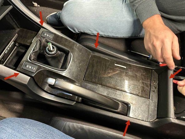 Slide both seats fully back. Using panel pop tools, pry very carefully starting from the back, and working your way around the edge until you feel each clip come free.