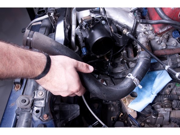 Remove the radiator cap and drain roughly 1 quart of coolant. Drain just enough so you can remove the upper rad hose without making a mess in your engine bay.