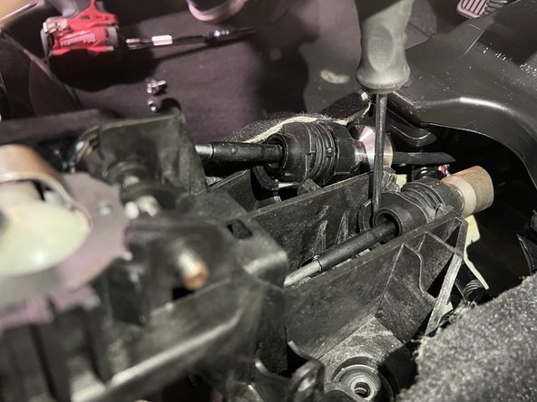 Unlock the shifter cable by depressing the clip with a flat tip screwdriver.