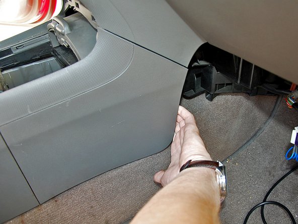 Reach behind the front lower side on each side of the center console and pull gently to unsnap it