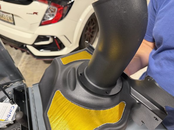 While holding the velocity stack, set the intake tube onto the airbox, lined up with the velocity stack bolt holes.