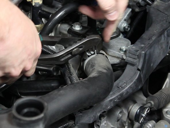 Using a pair of pliers, slide the hose clamps back. Remove the upper radiator hose.