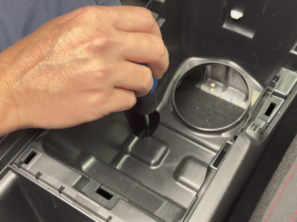 Remove the two 10mm mounting bolts under the cup holders.