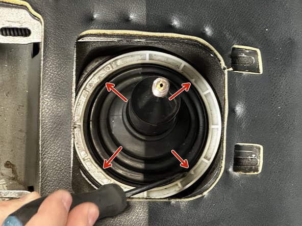 Use a flat-tipped screw driver, unclip the dust boot cover by prying outward. There are four clips at each corner.