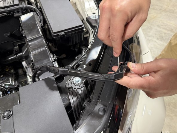 Unclip the wiring harness from its plastic guide along the front of the bay so it can be re-routed.