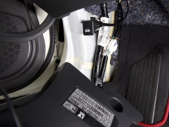 Route the wiring harness behind the kick panel and upwards toward the fuse box.