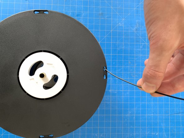 Take the end of the filament and thread it  through one of the holes at the edge of the reel to prevent it from unravelling.