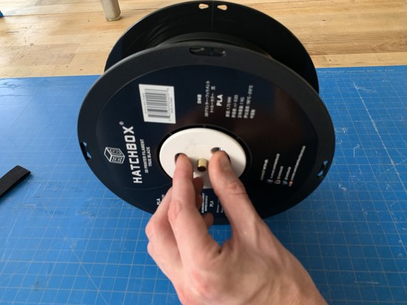 Grasp the hub going through the middle of the reel and unscrew it.  It may be a little stiff but it will thread off.