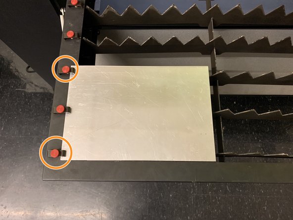Lay your sheet on the work table surface, and slide one edge underneath the thumbscrew clamps lining the left edge of the work table.