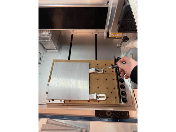 det finnes flere måter å feste materialet på, den enkleste er å bruke L braketten som står i maskinen og 2 klemmer, L braketten gjør slik at materialet alltid har en kjent plassering innenfor arbeidsområdet og klemmene fester materialet langs kanten uten å komme i veien