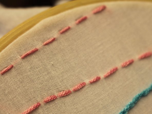 From the back of the fabric, insert needle and pull thread up through the front