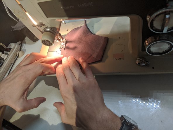 Line up all four of your layers and sew them together from the large point at the top (which will be the nose piece) down to the bottom flat edge (where your chin will go). Stop at the bottom edge but don't cut your string just yet.