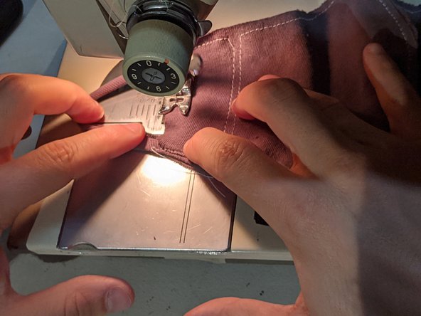 Sew down until you are about an inch away from the bottom and place the bottom strap between your two layers. Sew across it to the bottom and then turn the mask 90 degrees.