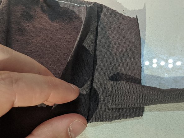 Unfold the layers and place the earloops about 1/8th of an inch away from the top of the mask. Fold your top layer back over and sew across it.