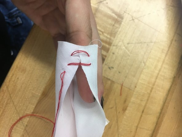 First, push the needle through the inside of one piece of fabric.