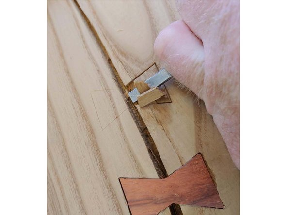 Hold the chisel with the blade at a low angle, with the bevel facing down. You want to try to match the bevel angle to the face of the wood.