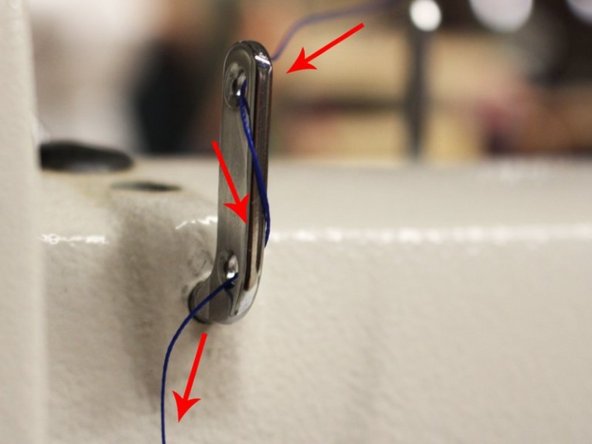The second thread holder is located at the front and also has two holes but is smaller. Pull the thread in the first step from the right to the left of the top hole of the holder. After, wrap the thread to the right side of the bottom hole and pull it through the left again.