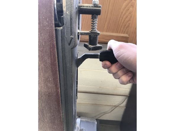 On the right hand side of the machine is a lever. Move it upward to reduce tension on the belt so it can slide off.