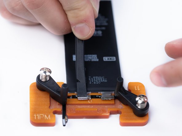 Hold the battery plate and BMS down together with a spudger and bend the excess of the plate backwards to secure it into position.