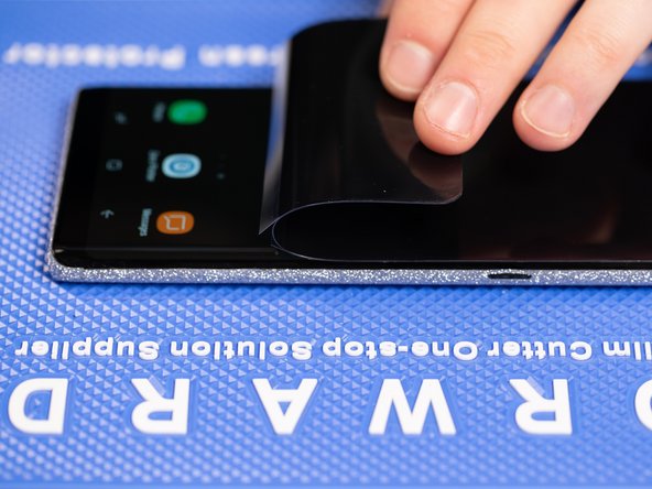 After peeling back the film to half way you will notice the film will split and will expose the sticky layer that will fix the film to the phone.