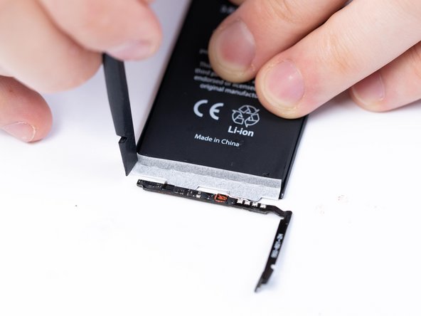 Spudger the protective sticker into place. It's split in the middle, make sure that when you're applying the flat side of the sticker is facing away from the BMS.