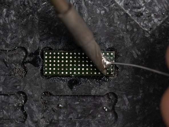 Lower your soldering tip down to your chip along with your solder wire. Press the solder wire against the tip until the wire melts and creates a small ball.