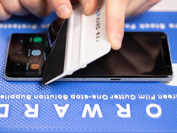 With your application tool slowly slide it along the film until you reach the end of the phone.