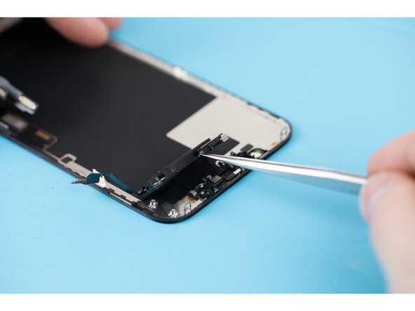 Once you've taken the screws out you'll be able to flip the speaker assembly over and place it away from the top edge of the display. Use a tweezers and carefully fold the speaker over.