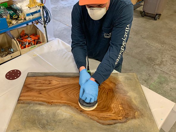 Use the sandpaper included in the kit to sand the river table top in steps, starting with 120-grit sandpaper to remove any lines left behind by the tape or any bubbles.