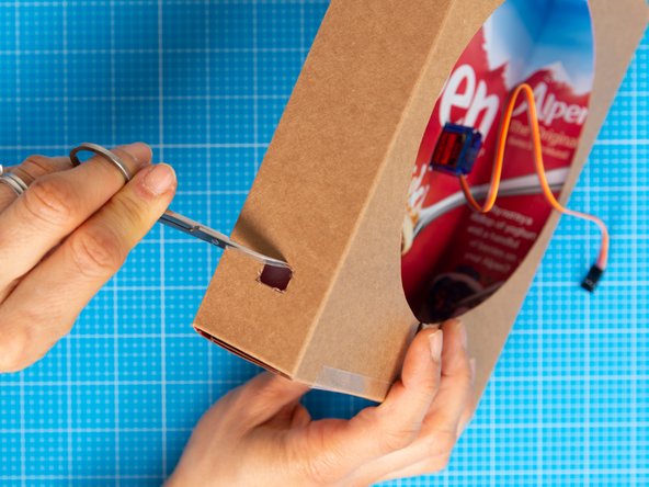 Open the hole using the nail scissors until it is large enough to pass the smaller end of the micro USB lead through.