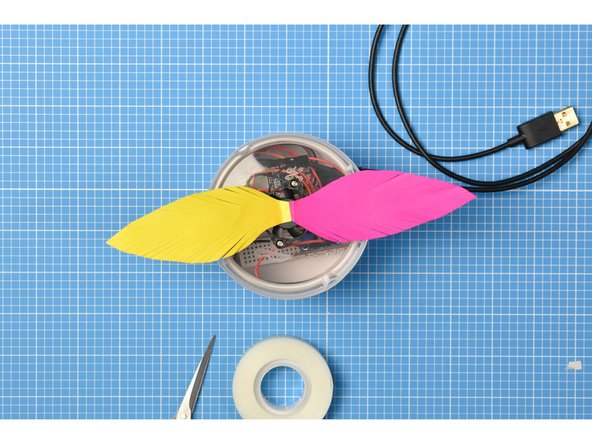 One by one, stick each feather to the central hub of the fan, making sure that the fan is still able to turn.