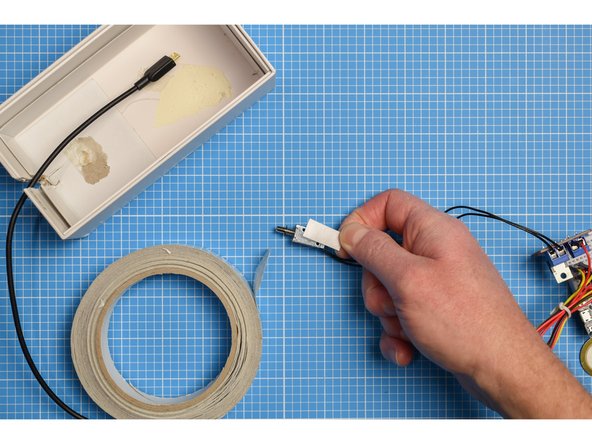 Using a small piece of double-sided tape, carefully position and stick the solenoid inside the box.