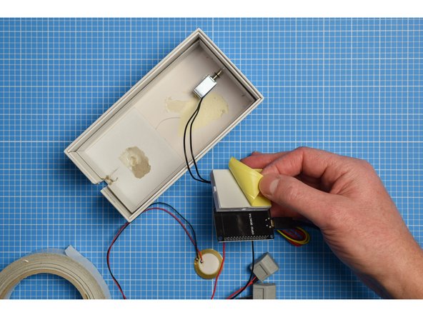 In most cases, the breadboard will already have a self-adhesive pad on the rear (use double-sided tape if not). Peel away the protective layer and stick the breadboard inside the box.