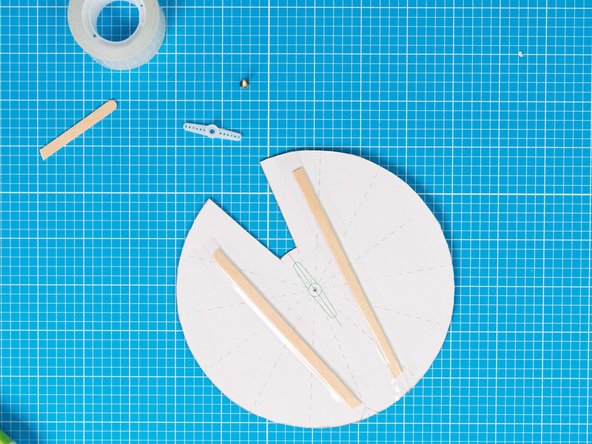 Fix the stirrer sticks  across the wheel with tape. Trim  to size if necessary. The supports  will keep the wheel  straight when  mounted on the device.