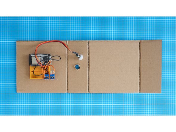 Mount the breadboard assembly onto the 1st segment of the cardboard as shown here. The breadboard has a double-sided tape backing which can be used to attach it.