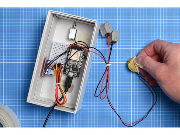 Attach a small piece of double-sided tape to the rear (the brass disc) of the piezo sensor and mount on the inside of the outer sleeve or lid of the box.