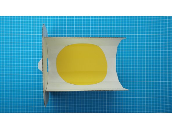 Using double sided tape stick (or glue) stick the coloured circle in the middle of the faceted curve of the enclosure.