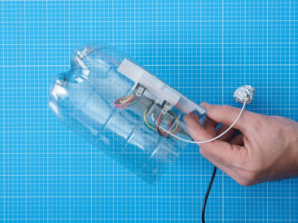 Secure the breadboard assembly inside the bottle by attaching the cardboard to the edge of the bottle with a bulldog clip.