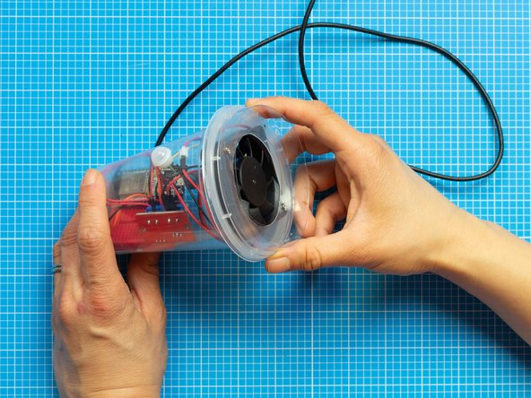 Close the top tub with the lid assembly, carefully folding in any jumper cables that might be in the way.