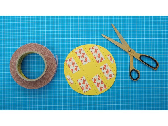 Using double sided tape stick (or glue) stick the coloured circle in the middle of the faceted curve of the enclosure.