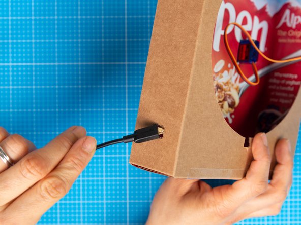 Open the hole using the nail scissors until it is large enough to pass the smaller end of the micro USB lead through.