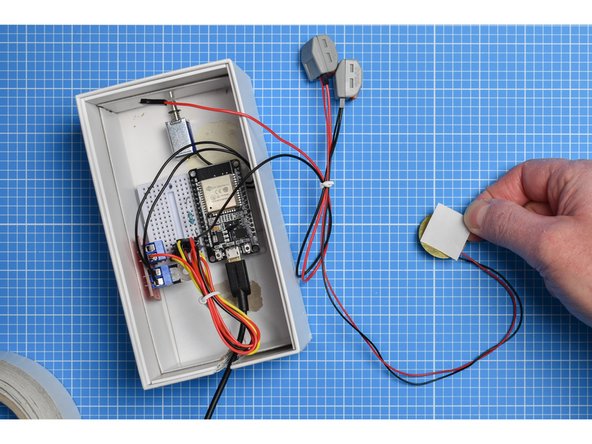 Attach a small piece of double-sided tape to the rear (the brass disc) of the piezo sensor and mount on the inside of the outer sleeve or lid of the box.