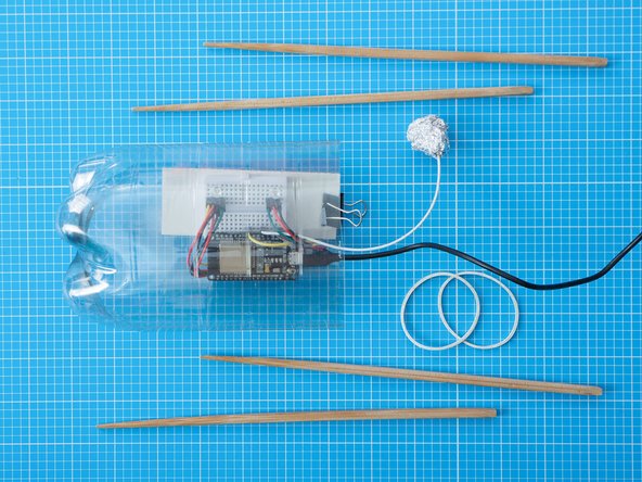 Secure the chopsticks to the outside of the bottle using rubber bands or sellotape. Align the chopsticks so none of them are directly in front of the LEDs.