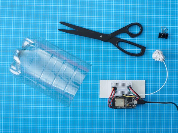 Cut the plastic bottle in half with scissors and keep the bottom section.